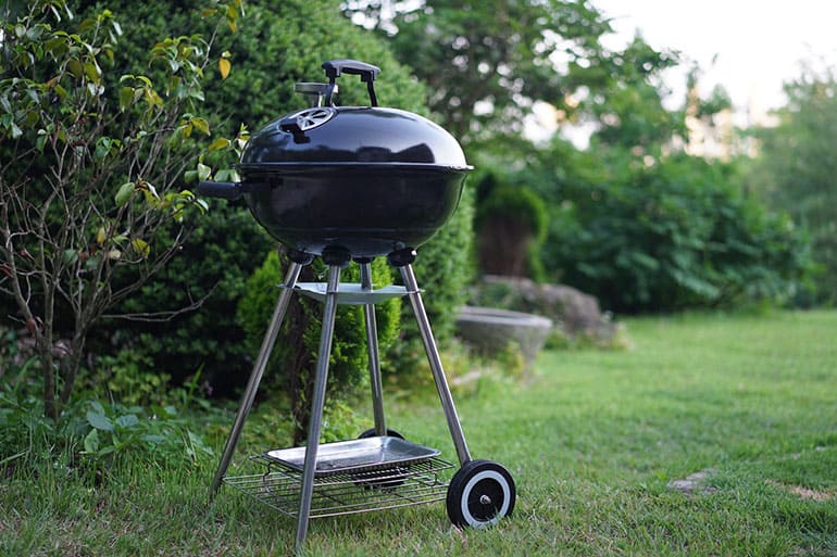 charcoal grill resting on garden lawn