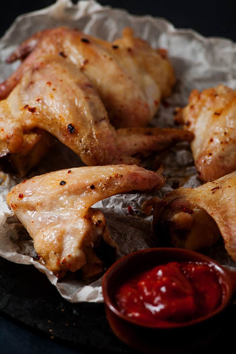 crispy chicken wings sitting next to bbq sauce on table