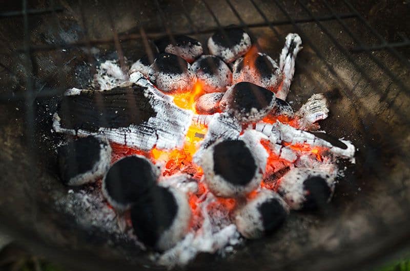 charcoal embers lit at base of smoking charcoal grill