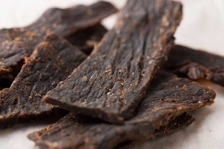 close up photo of dark beef jerky on table
