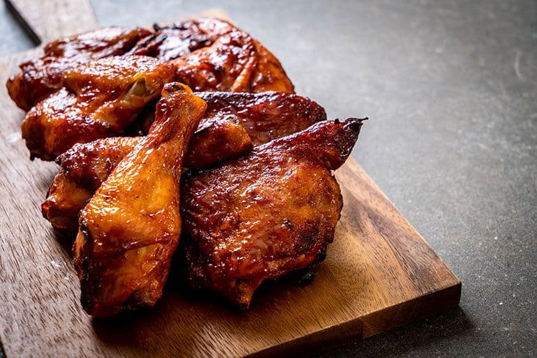 chicken leg quarters cooked and resting on wooden kitchen counter