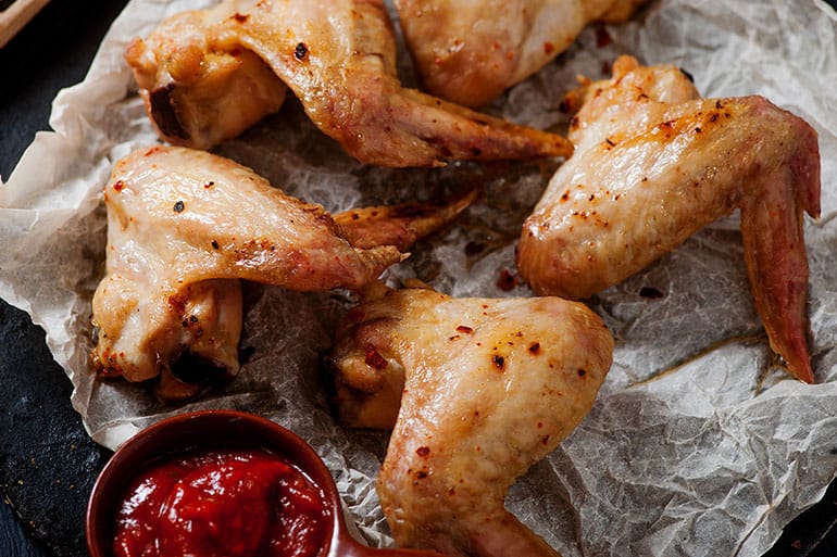 bbq grilled and smoked chicken wings served on parchment paper with tangy side dipping sauce