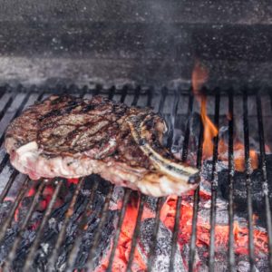 tomahawk steak seared over charcoal grill