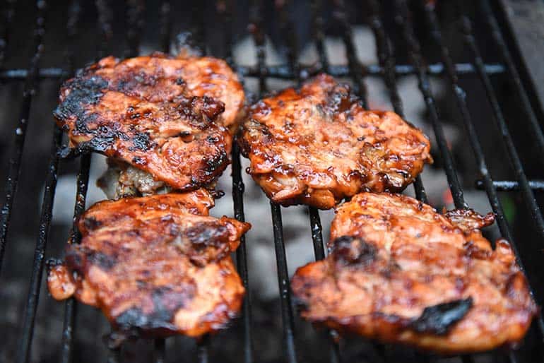 chicken quarters resting on bbq smoker cooking grates