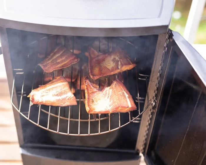 Close up of open smoker cooking red salmon fillets