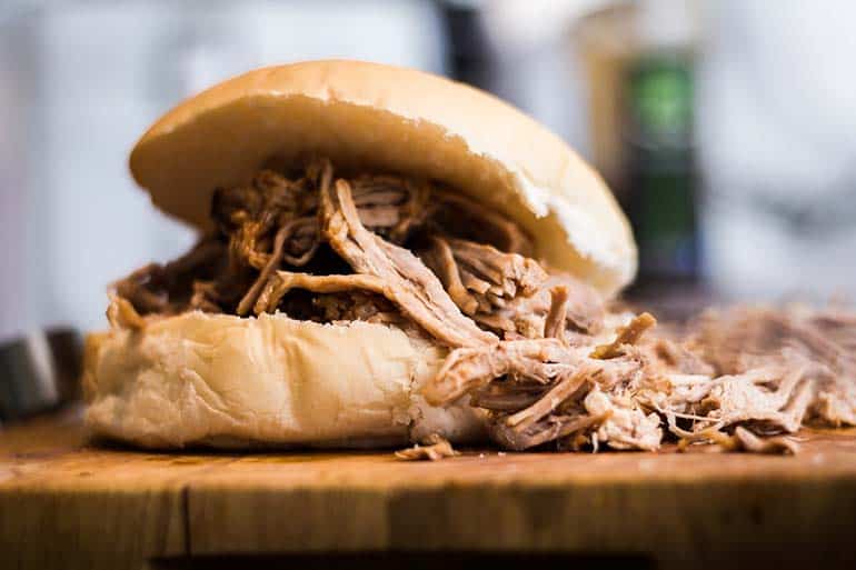pulled pork in bun resting on table