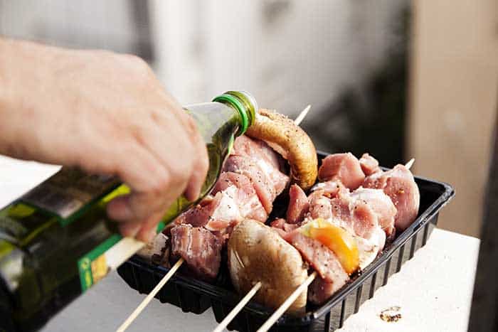 applying oil to chicken skewer kabobs