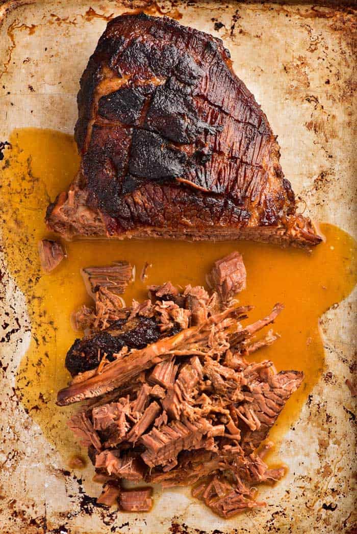 sliced brisket on chopping board pulled into small chunks