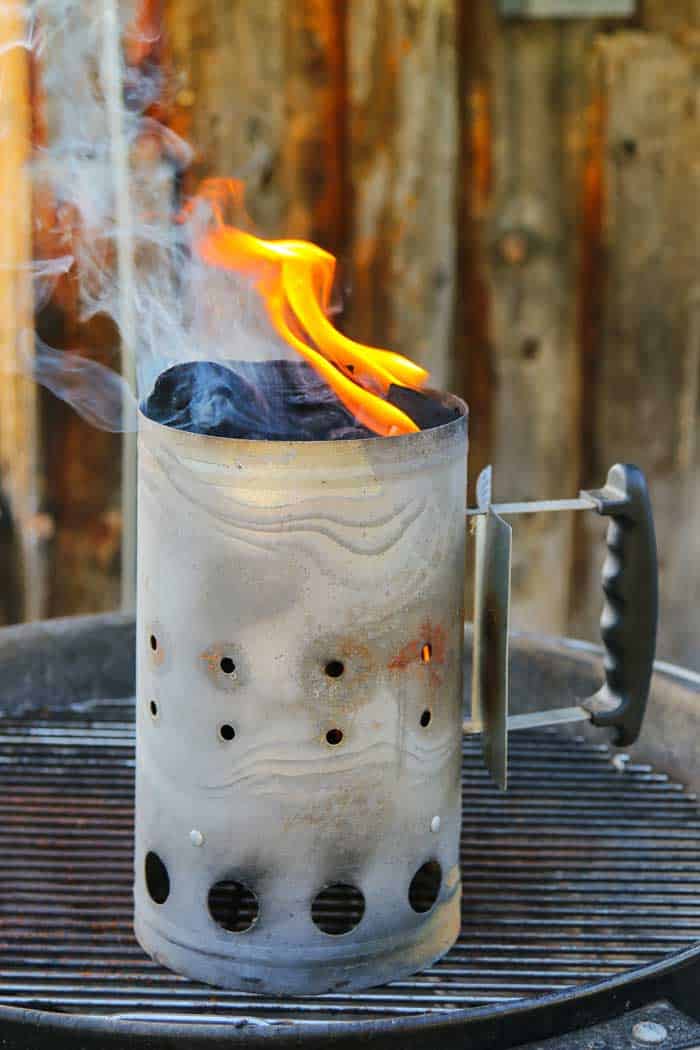 lit charcoal chimney placed on grill grates