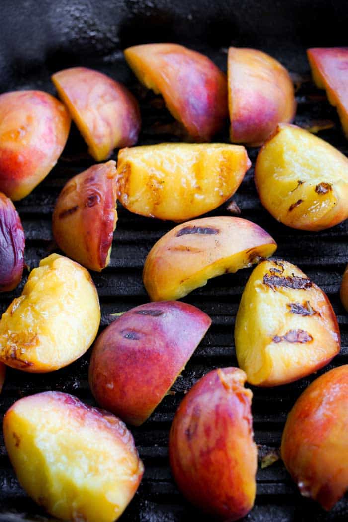 charred peaches cooking on stainless steel bbq grill