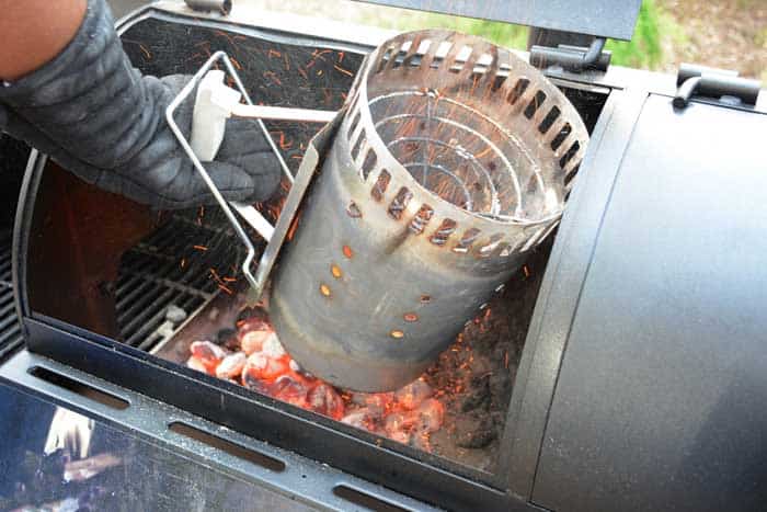 charcoal chimney emptying coals into smoker chamber