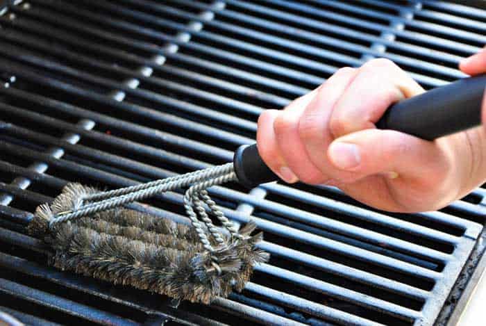 using brush to clean smoker grates