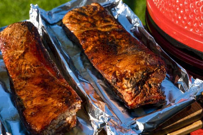 Two racks of grilled pork ribs on foil