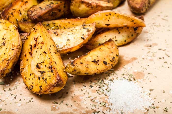 delicious potato wedges resting on parchment paper