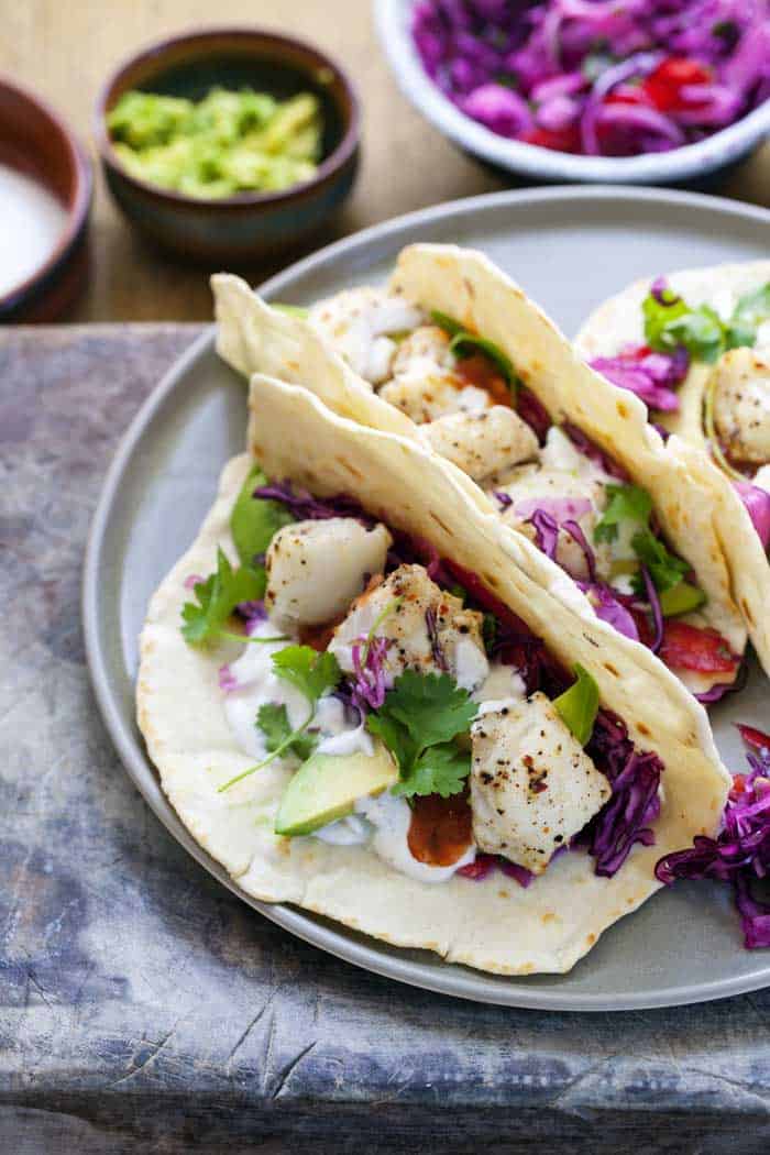 grilled fish tacos ready to eat served with guacamole and beetroot coleslaw