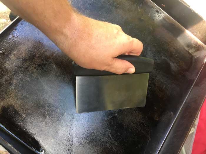 Cleaning flat top grill with scraper