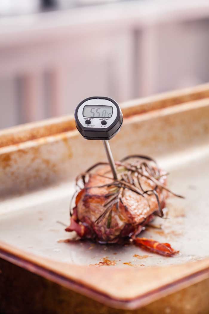 thermometer probe in pork resting on cutting board