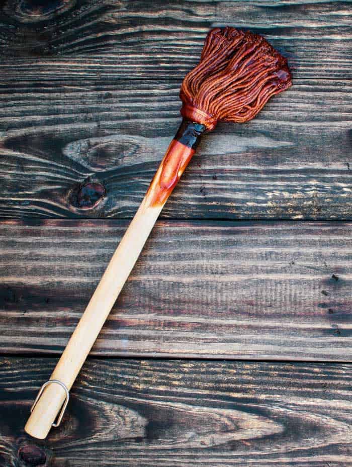 BBQ Mop or brush over top a rustic wood table / background with barbecue sauce on end