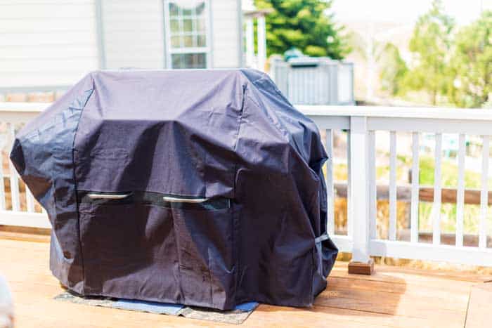 Large gas grill covered with black cover to protect from weather elements