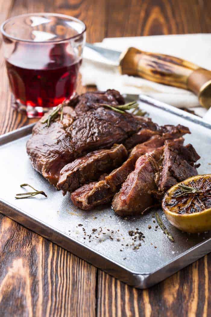 Medium rare grilled marinated beef flank steak on silver plate