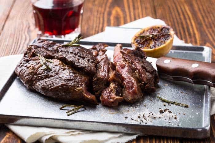 Medium rare grilled marinated beef flank steak on silver plate