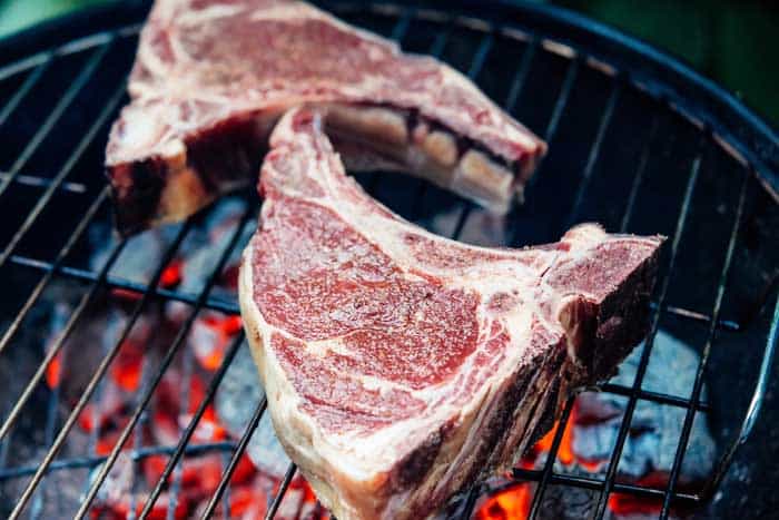 Two ribeye beef steaks on the charcoal grill