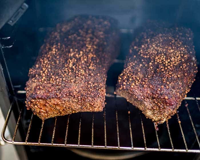 beef brisket for pastrami in smoker with rub ingredients on surface