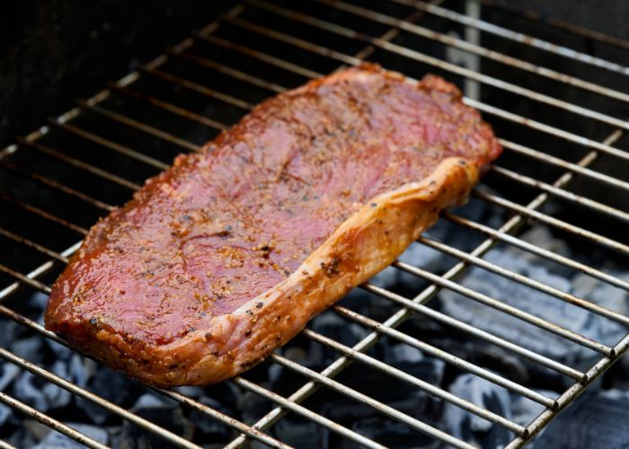 beef rump steak on stainless steel charcoal grill grates