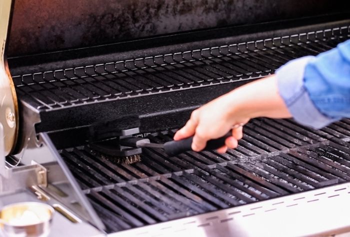 scraping burned food off gas grill grates with a wire brush