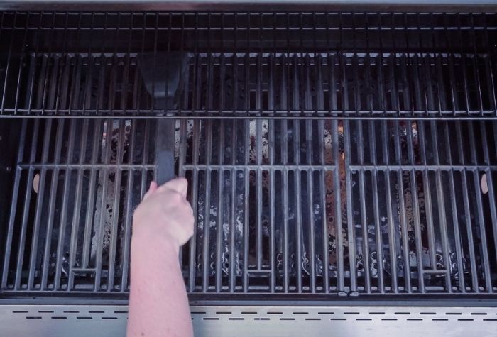 topdown view of cleaning gas grill grates with a wire grill brush