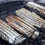 cod white fish smoking over coals in fish baskets