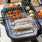 Person cooking on an electric grill with tongs and aluminum foil