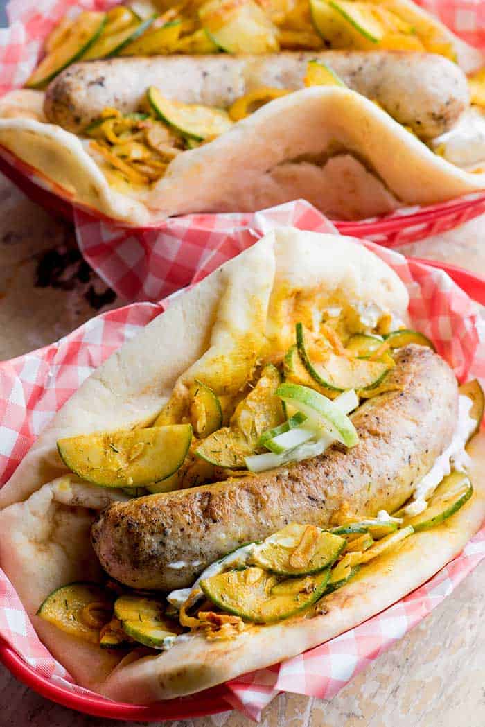 grilled bratwurst served in toasted flatbread and onion zucchini sauerkraut and yellow mustard dressing