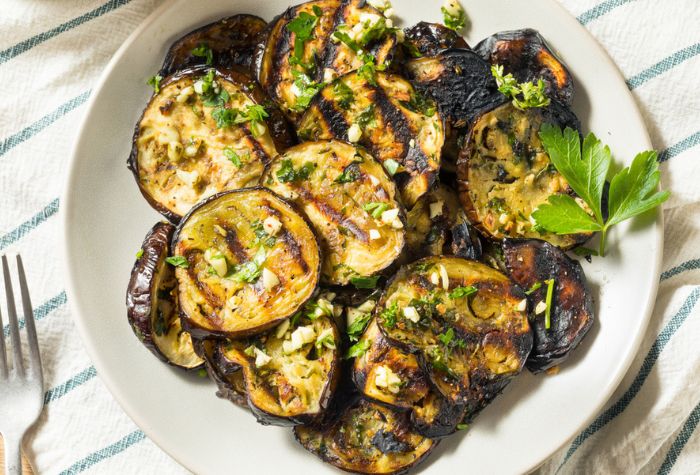 charred eggplant slices served fresh from grill garnished in chopped garlic and parsley marinade