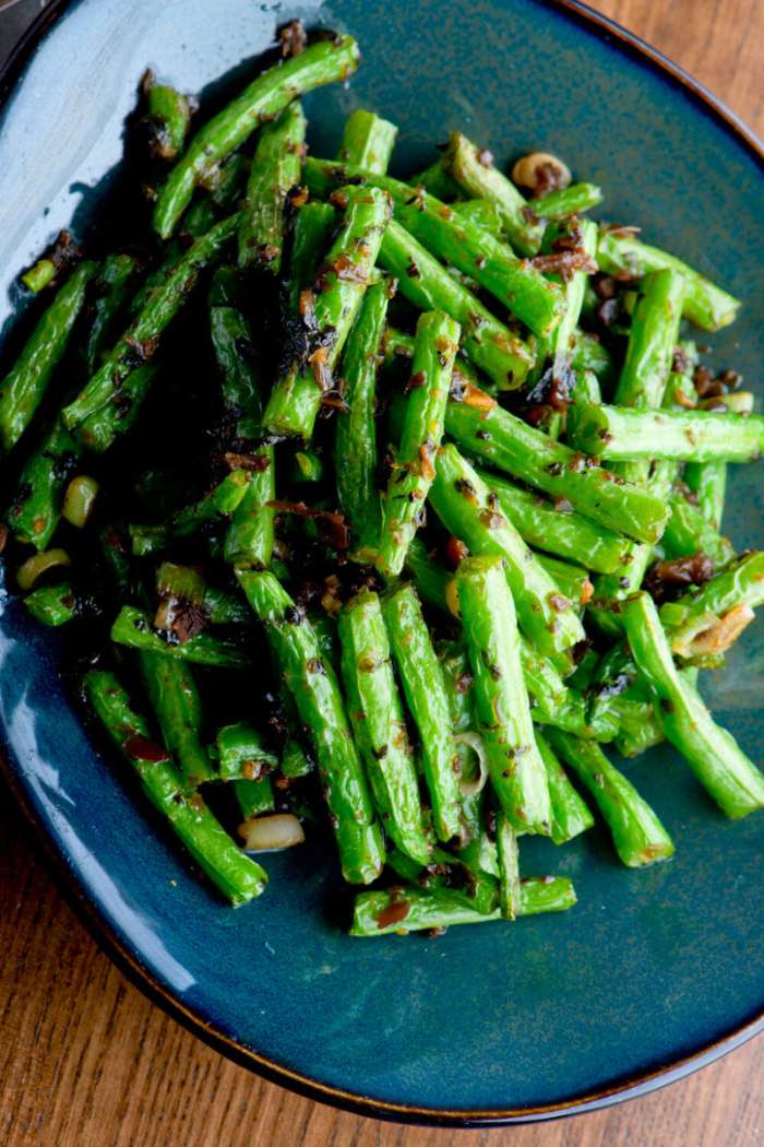 grilled green beans served on plate and seasoned with crushed garlic, salt and oil