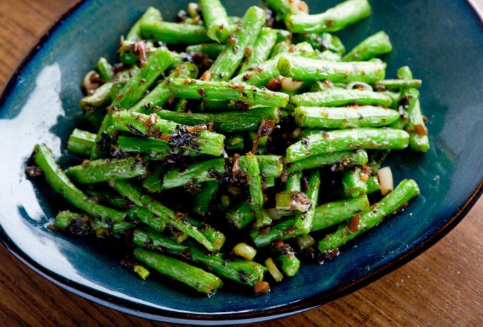 grilled green beans served on plate and seasoned with crushed garlic, salt and oil