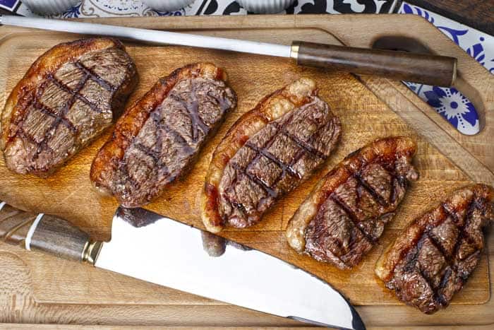 grilled picanha beef steak on chopping board and chef's knives