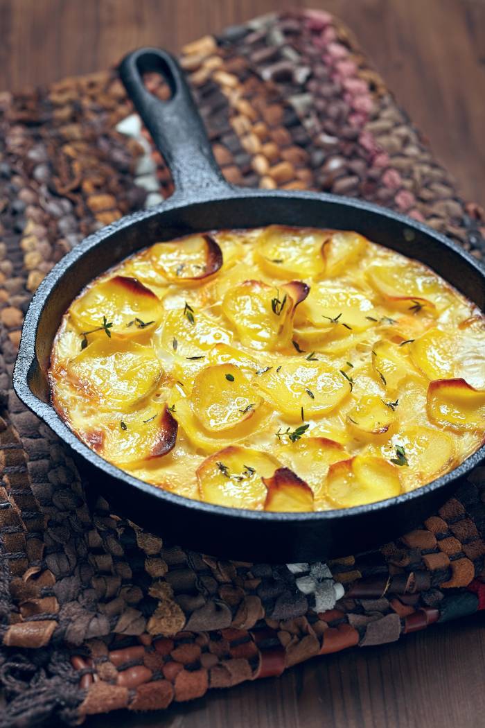 scalloped potatoes in cast iron skillet with slight crispy char and melted cheese