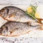 grilled sea bream fish on chopping board rosemary lemon peppercorns