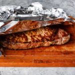 grilled steak resting on wooden board covered with aluminum foil