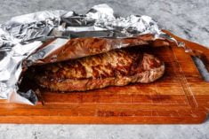 grilled steak resting on wooden board covered with aluminum foil