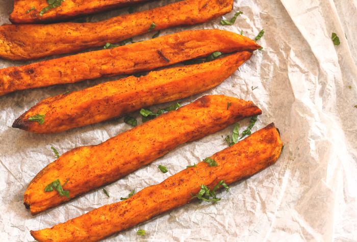 grilled sweet potato fries topped with chopped parsley garnish and served in parchment paper