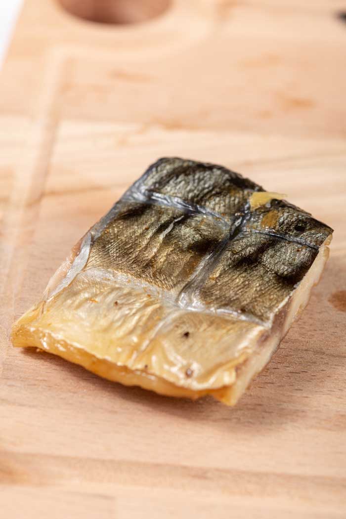smoked mackerel cut into small fillet piece resting on chopping board