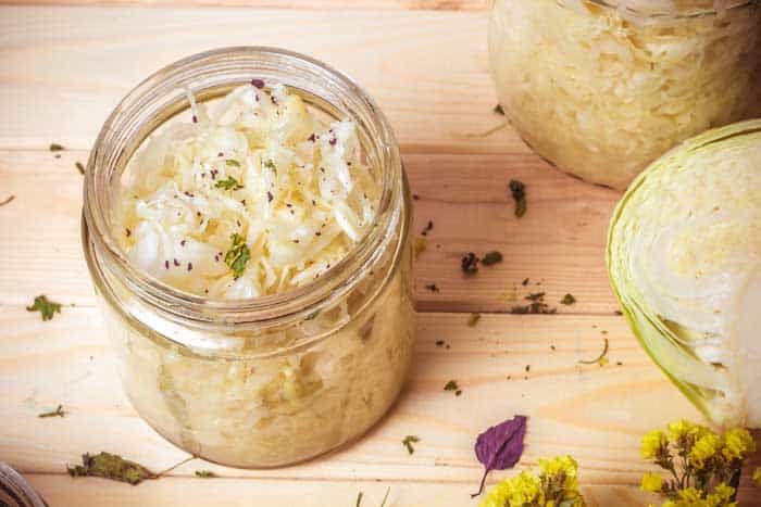 fermented shredded cabbage sauerkraut with garnish in mason jar