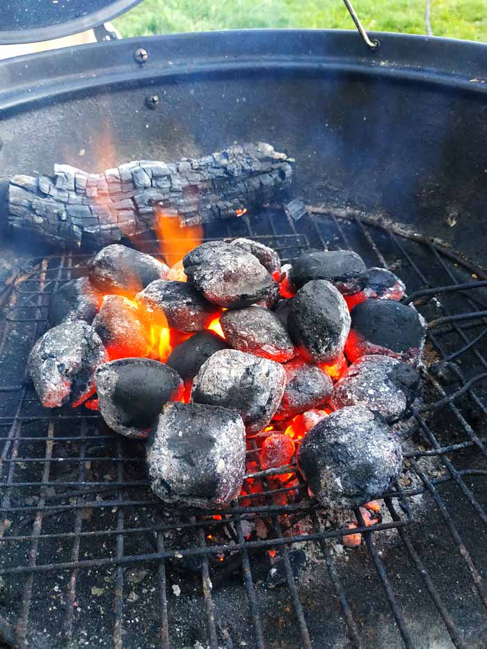 lit charcoal briquettes arranged in middle of charcoal grill chamber