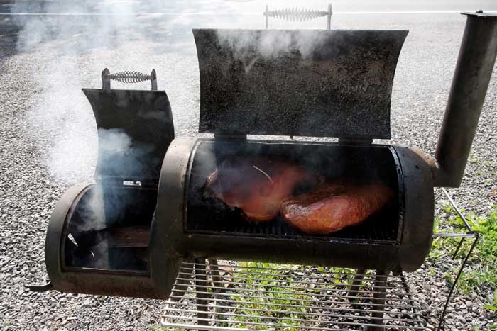open offset smoker cooking pork shoulder and brisket