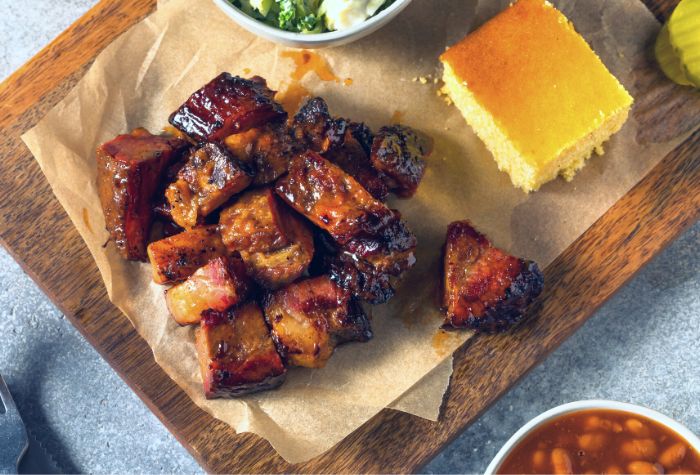smoked chuck roast poor man's burnt ends served on chopping board with bbq sides