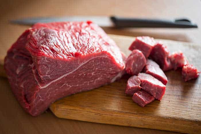 raw beef chuck diced on wooden board