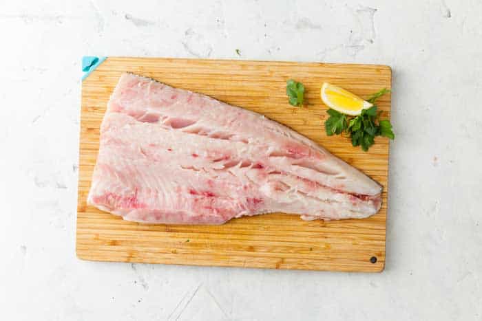 raw filleted catfish on chopping board