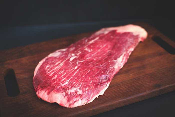raw flank beef on wooden board